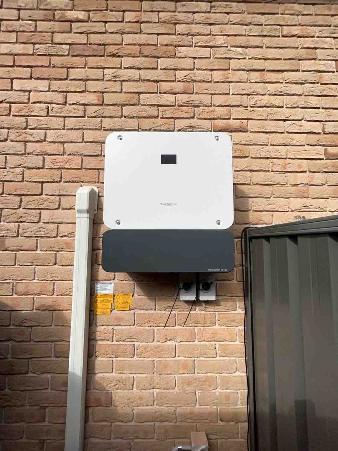 Solar inverter installed on a brick wall, showcasing electrical efficiency and modern design.